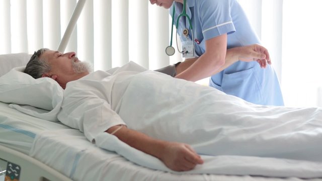 Female medicine nurse measuring blood pressure to senior patient in a hospital room