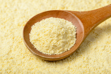 raw corn flour in the wooden spoon, tilt shift lens