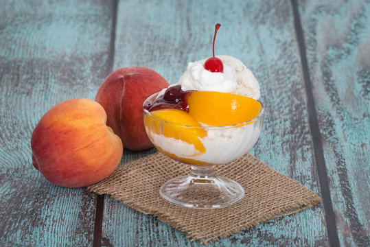 Vanilla peach melba ice cream with peach fruits on wooden vintag