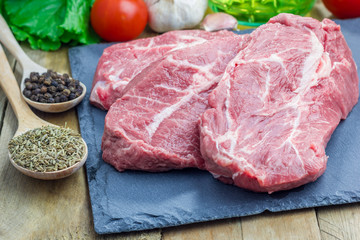 Raw beef steak with seasoning on a black slate tray
