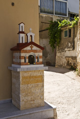 Fototapeta na wymiar Kandylakia, a Greek Mini-Chapel. Kandylakia is a tiny chapel built by the side of the road or in a city as a public praying place. It is a shrine built in the shape of a small Orthodox chapel.