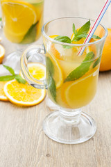 Orange fresh drinks with ice and mint on wooden table, selective focus