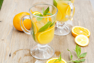 Orange fresh drinks with ice and mint on wooden table, selective focus