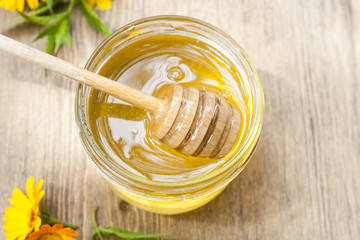 Linden honey in jar and calendula blossoms on wooden table, selective focus