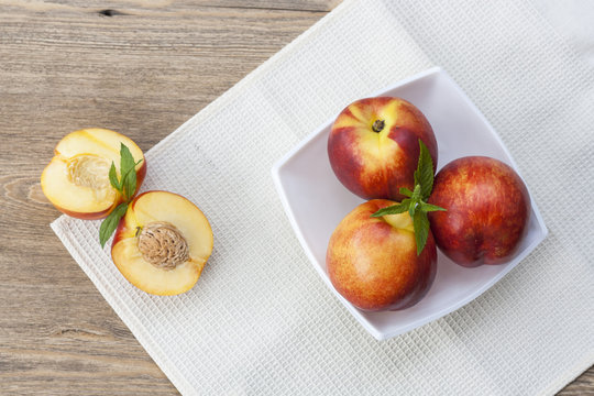 Juicy nectarines in a white plate on the table and slice and nectarines, selective focus