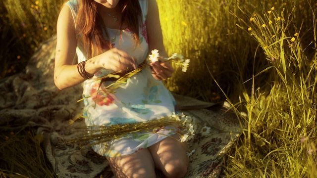 Girl kneel on the meadow and doing grommet from flowers
