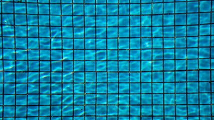 Blue ripped water in swimming pool with ceramic tile mosaic in background