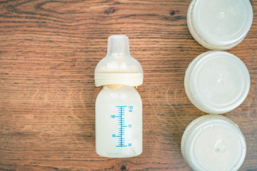 Top view of baby bottle with milk and a measuring scale on the background of a lot of full bottles...