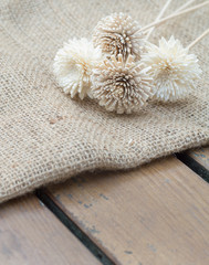 Dry flowers on burlap hessian sacking on the wooden table.