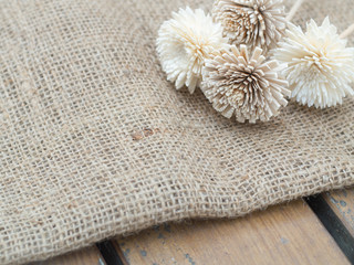 Dry flowers on burlap hessian sacking on the wooden table.