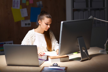 Young woman working in office, sitting at desk