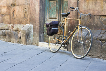 Obraz premium Yellow bicycle with bag against a stone wall