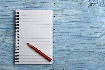 Notepad with red pencil on old wooden table