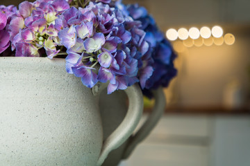Earthen cup with hydrangea with blurres kitchen in background