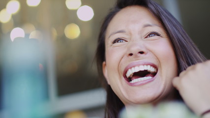 Camera moves around an attractive woman talking at a cafe table in slow motion - Powered by Adobe