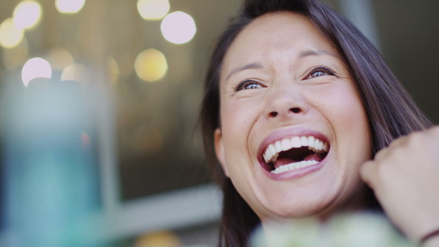 Camera moves around an attractive woman talking at a cafe table in slow motion