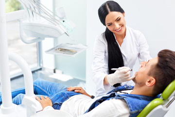 Obraz premium Famele dentist and man in dentists office. Dentist and Patient