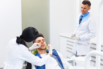 Dentist with Assistant Examining Teeth in the Dentists Chair.