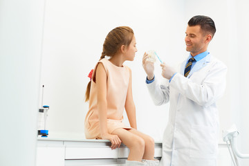 Dentist showing a girl how to brush her teeth.
