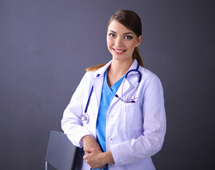 Beautiful female doctor standing near stool isolated gray
