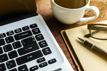 Laptop and cup of coffee on old wooden table