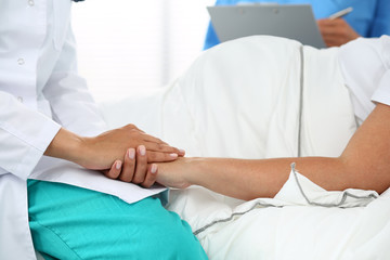 Friendly female medicine doctor's hands holding pregnant woman's