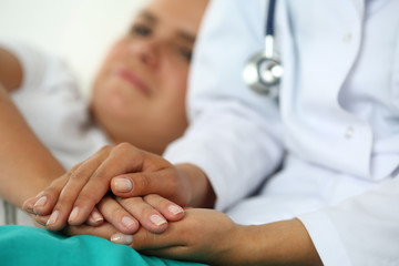 Obraz na płótnie Canvas Friendly female doctor's hands holding patient's hand