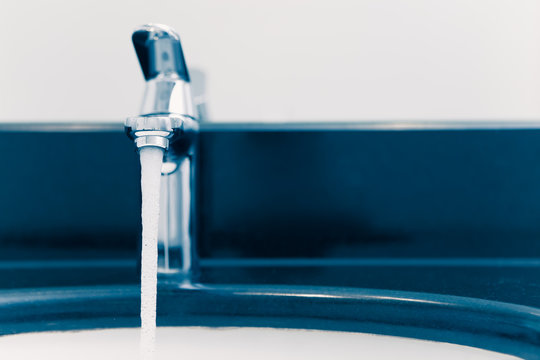 faucet with flowing water, blue tone