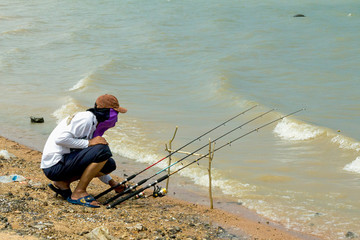 Fisher man with fishing rod on the beach 