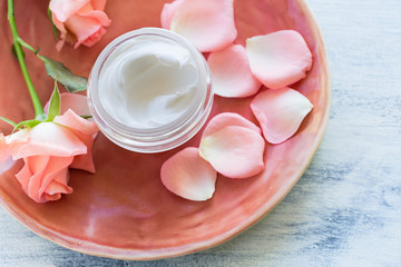 Obraz na płótnie Canvas Cosmetic cream on antic plate with rose flowers 