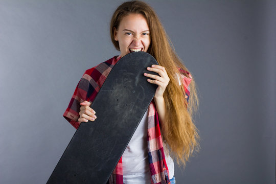beautiful young girl chews on a skateboard