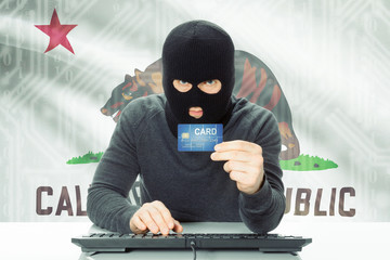 Hacker holding credit card and USA state flag on background - California