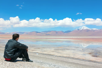 Fototapeta na wymiar Man sitting alone on the shore of Laguna Colorada, Bolivia