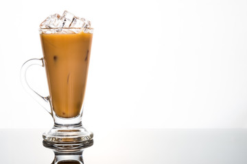 Refreshing ice cold coffee with milk in transparent glass flushed left