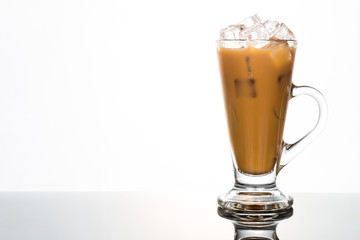 Refreshing ice cold coffee with milk in transparent glass flushed right