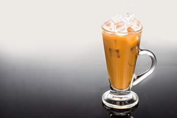 Refreshing ice cold coffee with milk in transparent glass flushed right