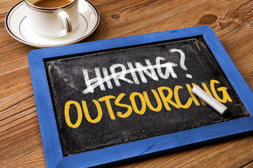 hiring or outsourcing concept handwritten on blackboard