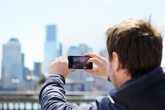 Tourist taking mobile photo of skyscrapers