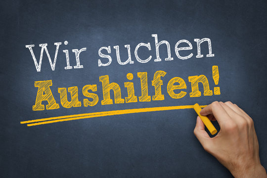 Hand schreibt Text "Wir suchen Aushilfen!" auf Kreidetafel