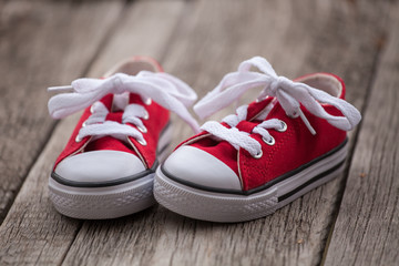 Red baby sneakers on wooden background