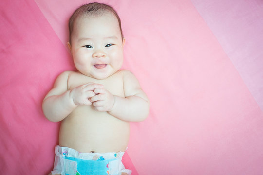 Asian baby girl smile on pink bed