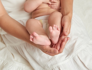 Obraz na płótnie Canvas baby legs in mother hands on white