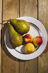 Fruit lying in a plate, standing on a wooden background.
