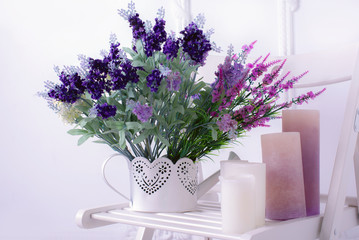 Fototapeta premium Still life of lavender flower and candles on a white chair close view