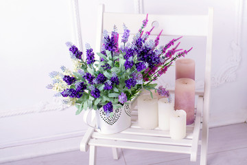 Still life of lavender flower and candles on a white chair