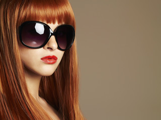 Beauty Girl in sunglasses. Healthy Red Hair. Beautiful Young Woman