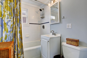 small bathroom with blue walls, and colorful shower curtain.