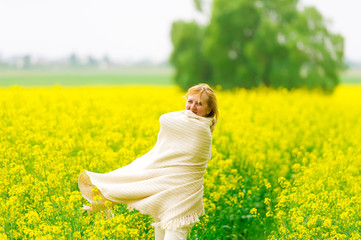 Fototapeta premium The beautiful woman dances on a rape field