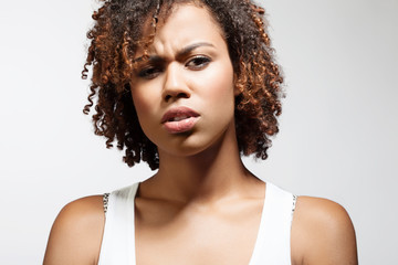Beautiful young woman with a doubting emotion on his face on a white background