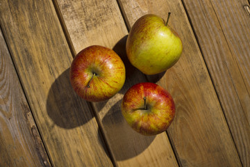 The apples lying on the wooden background.